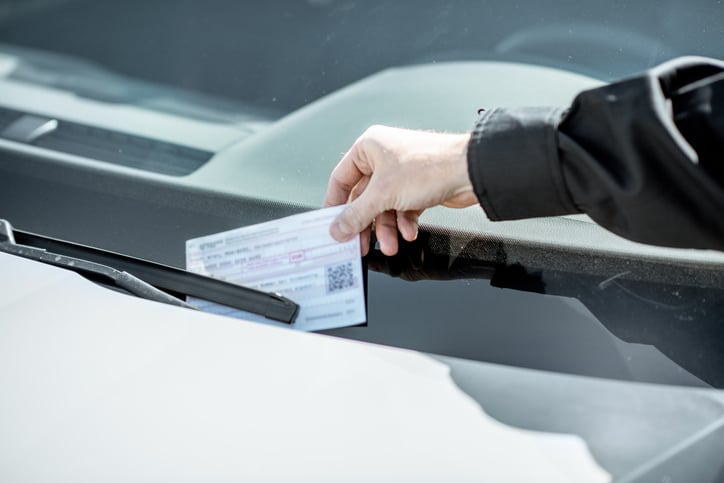 Agent déposant un PV sur un véhicule mal garé