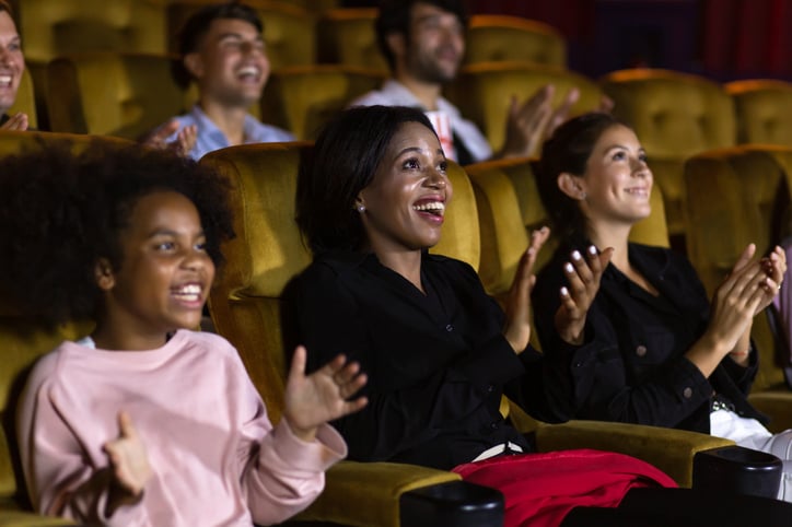 Trois personnes applaudissent à un spectacle