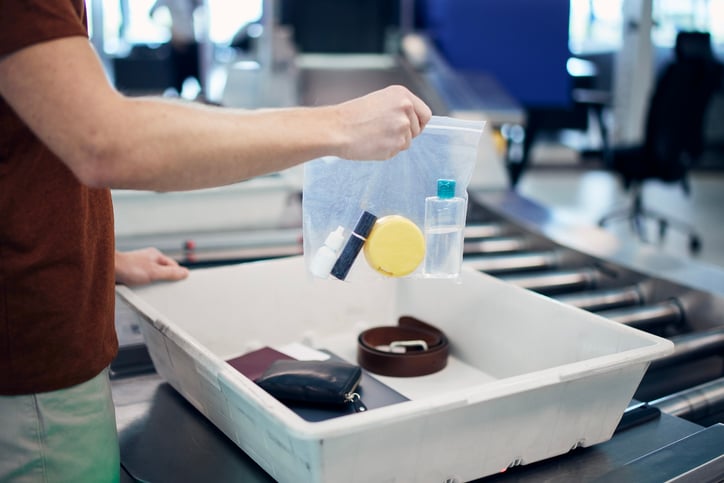 Une personne met ses affaires dans un bac à l'aéroport