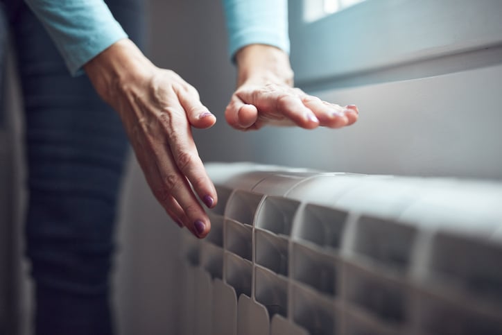 Une personne approche ses mains d'un radiateur