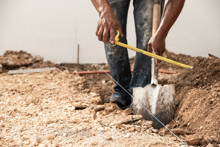 Un ouvrier creuse une tranchée sur un chantier