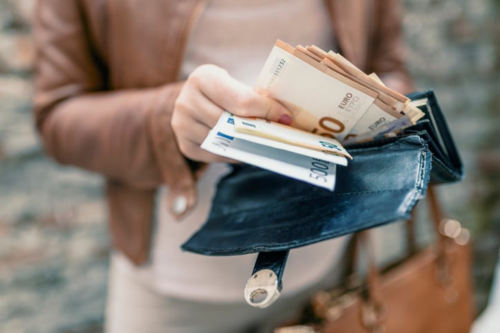 Une femme sort des billets de son portefeuille