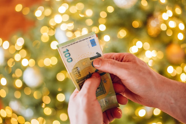 Un personne comptant des billets de banque devant des décorations de Noël