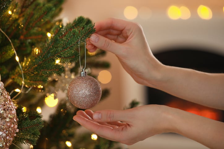 Une personne décore un sapin de Noël