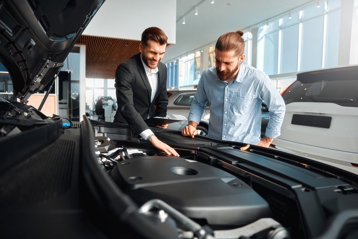 Un garagiste et concessionnaire montre le moteur d'une voiture à un client