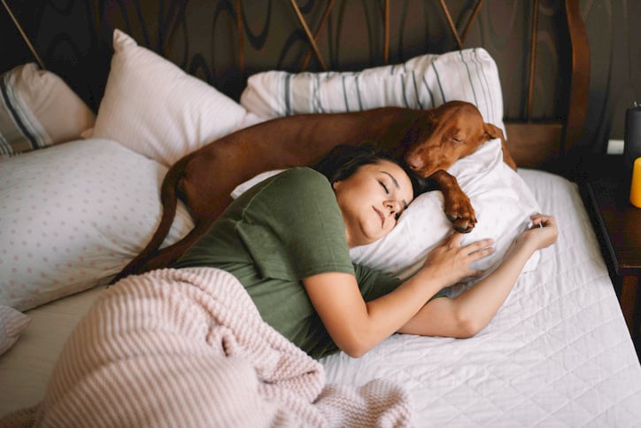 Une femme dort dans son lit avec son chien