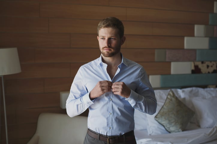 Un homme boutonne sa chemise