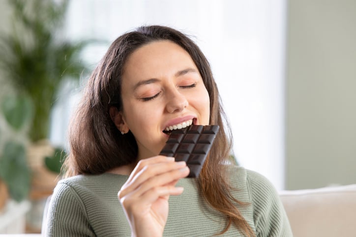 Une femme mange du chocolat noir