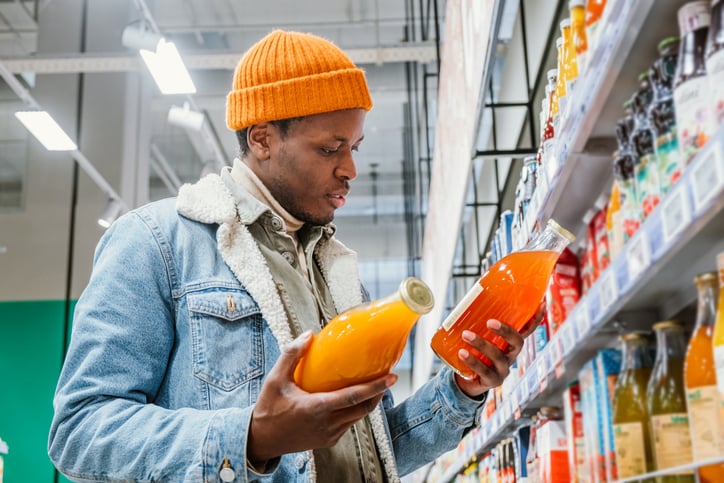 Un homme choisit un jus de fruit au supermarché