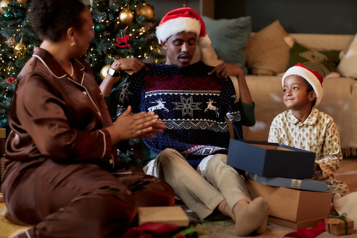 Un homme déballe un pull d'un cadeau de Noël