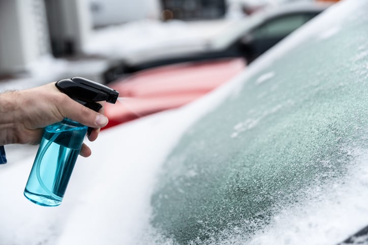 Un automobiliste dégivre son pare-brise avec du dégivrant