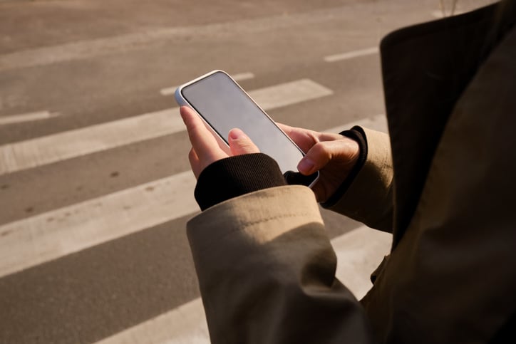 Une personne regarde son smartphone sur un passage piéton