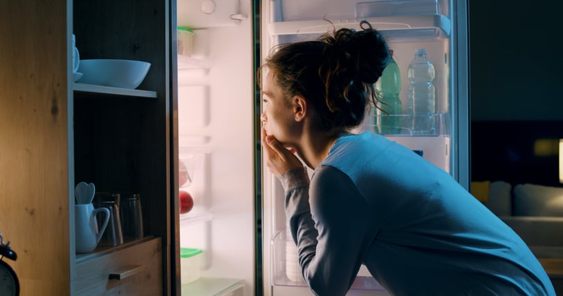 Une jeune femme regarde dans son frigo