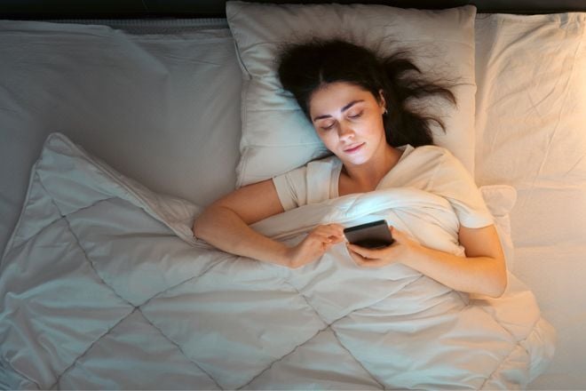 Une femme sans son lit sur son smartphone