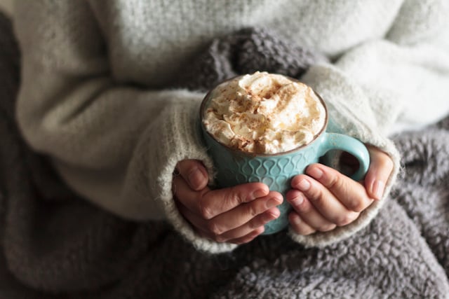 Une femme qui tient une tasse de chocolat chaud entre ses mains