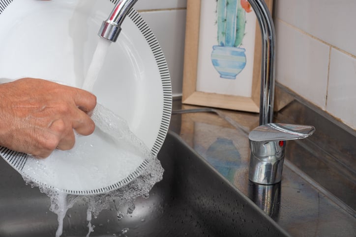 Une personne passe une assiette sous l'eau