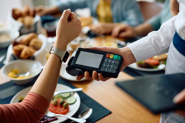 Une femme qui utilise sa montre connectée pour payer le restaurant 