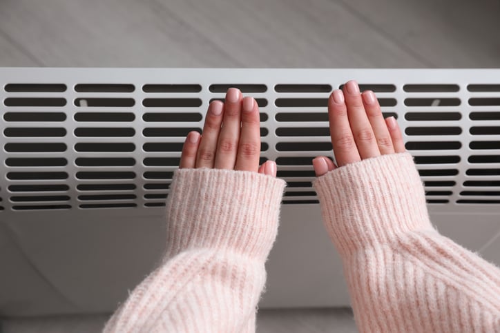 Une personne pose ses mains sur le radiateur