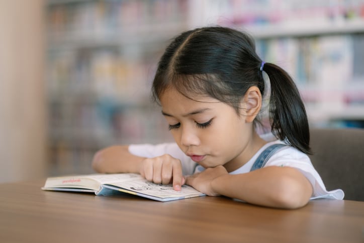 Une petite fille lit un livre