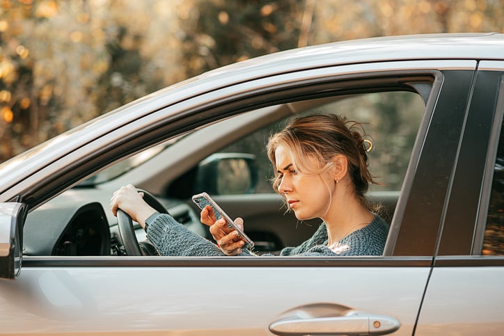 Une femme avec son téléphone au volant de sa voiture