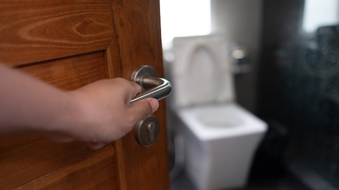 Un homme ouvre la porte des toilettes