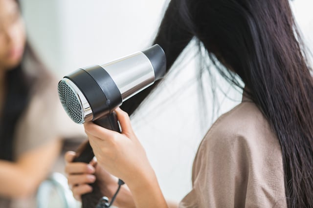 Une femme qui utilise un sèche-cheveux