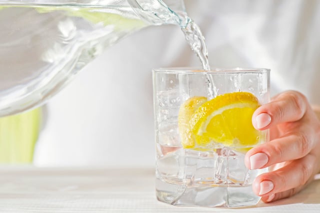 Une femme se servant un verre d'eau avec du citron