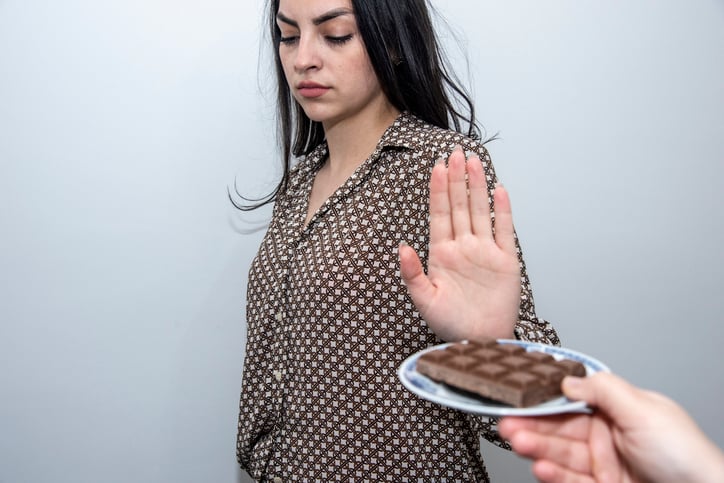 Une femme refuse la plaquette de chocolat qu'on lui tend