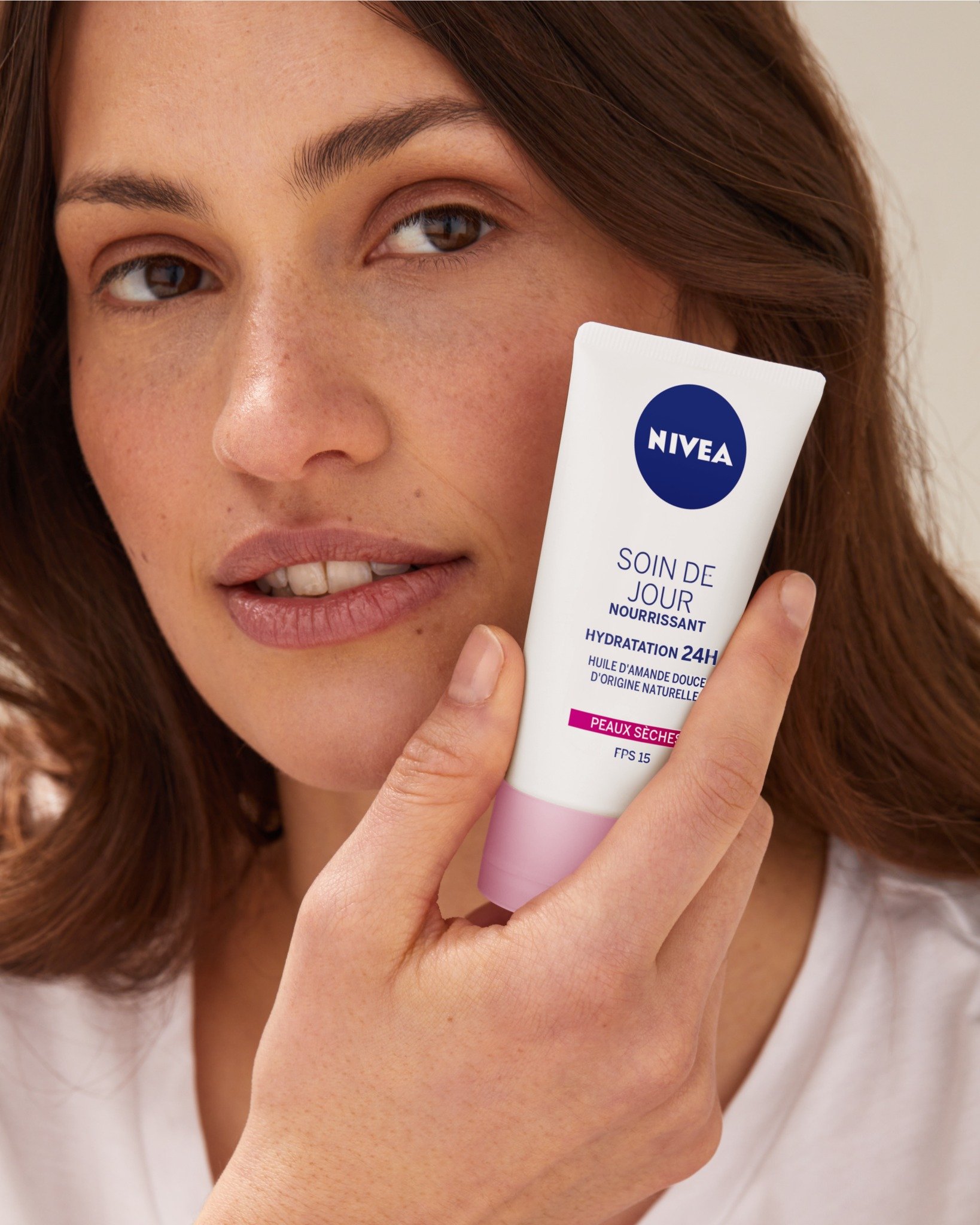 Une femme tient une crème Nivea