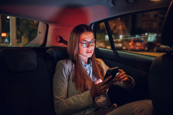 Une femme sur son smartphone à l'arrière d'une voiture