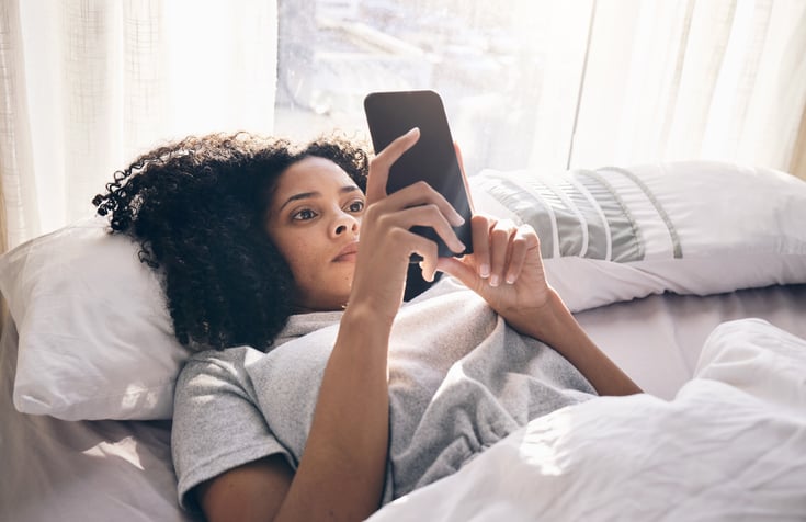 Une femme consulte son téléphone le matin dans son lit