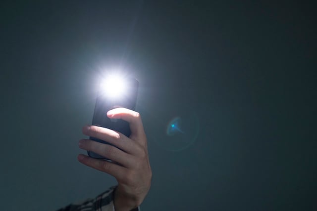 Une personne utilisant le flash de son smartphone