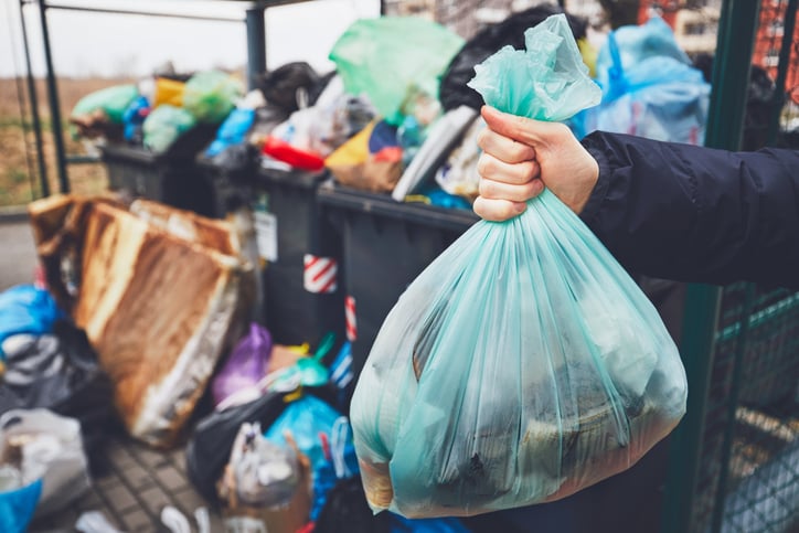 Un homme dépose ses déchets dans une poubelle