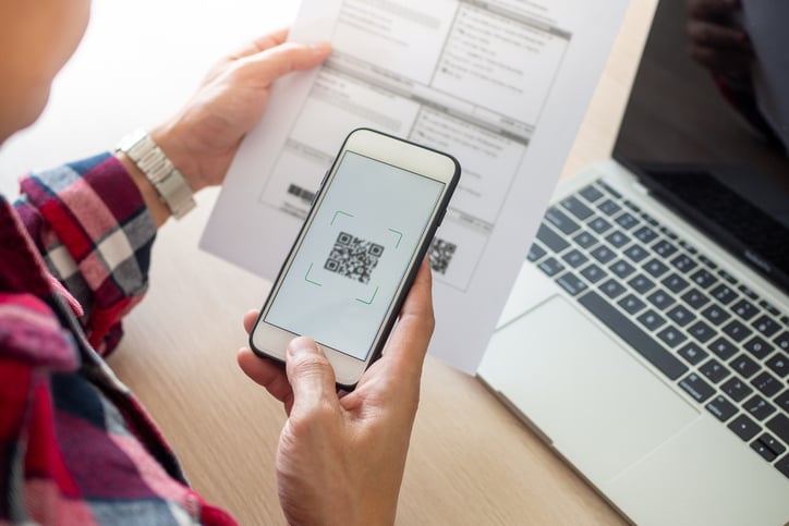 Une femme scanne un document avec un QR Code