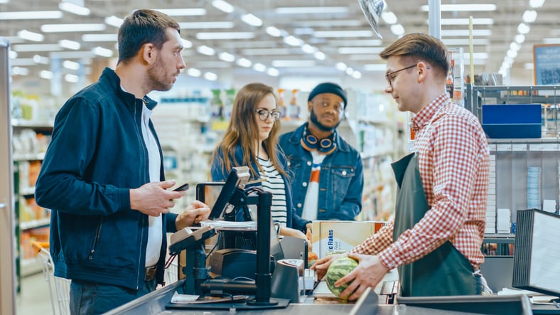 Un homme règle ses achats à la caisse d'un supermarché