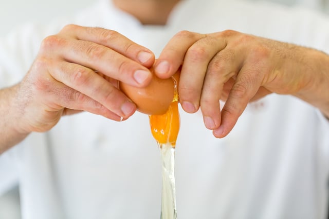 Un cuisinier en train de casser un oeuf