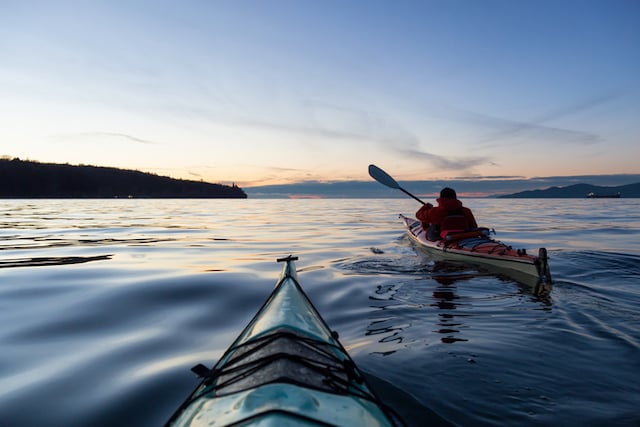 Deux personnes en train de faire du kayak pendant le coucher du soleil 