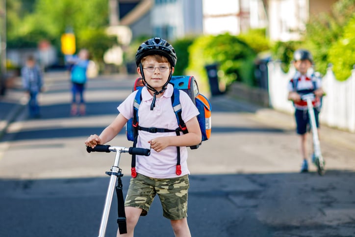 Un garçon va à l'école en trottinette