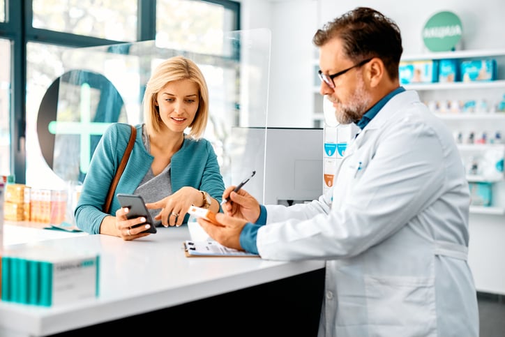 Une femme montre son smartphone à un pharmacien