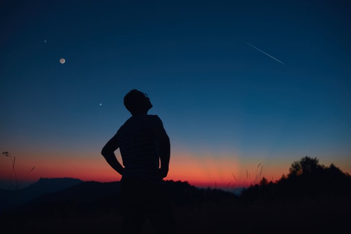 Un homme regarde le ciel au coucher du soleil