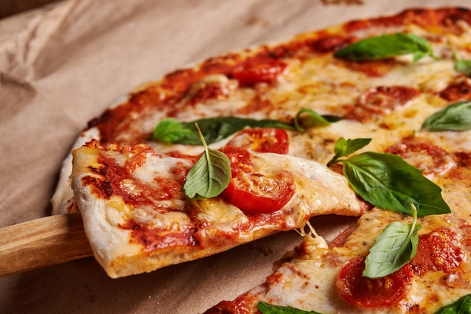 pizza aux tomates avec du fromage fondu et des feuilles de basilic