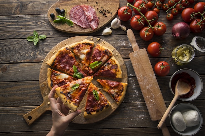 pizza aux tomates et salami coupée en parts