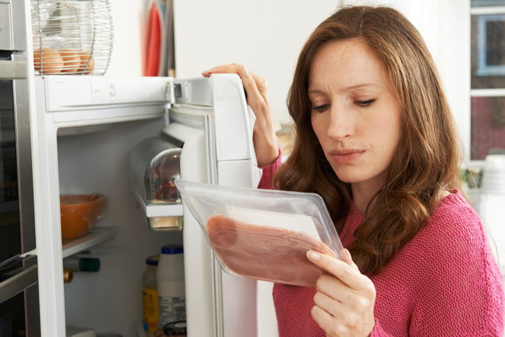 Une femme regarde un paquet de viande