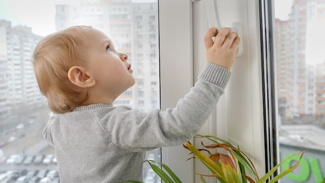 Un enfant qui tente d'ouvrir une fenêtre