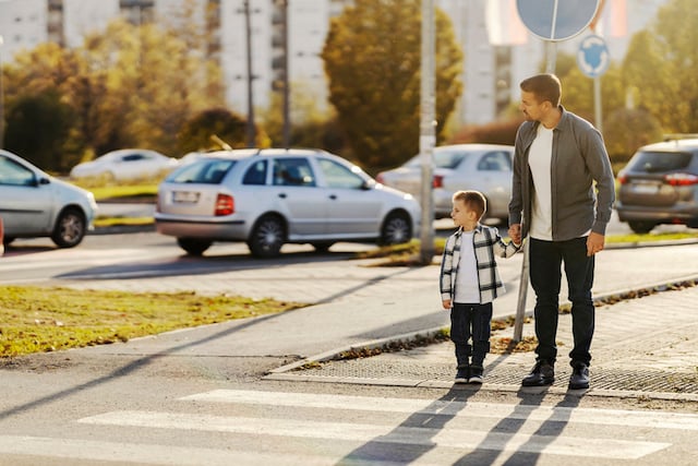 Un père et son fils traversant un passage piéton 