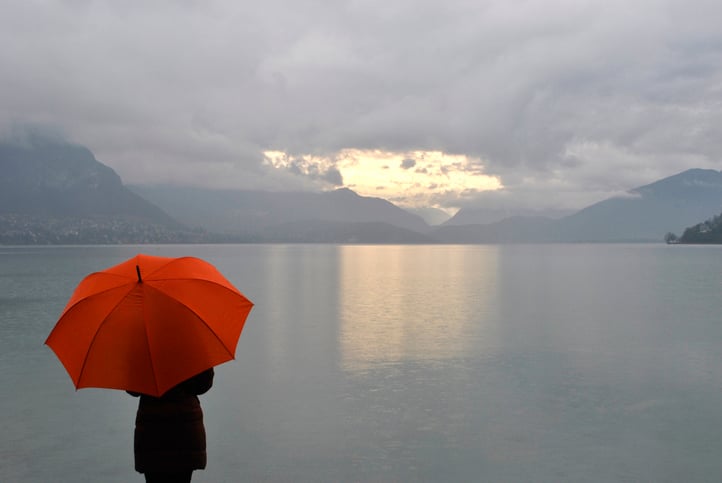 Une personne avec un parapluie face au lac d'Annecy