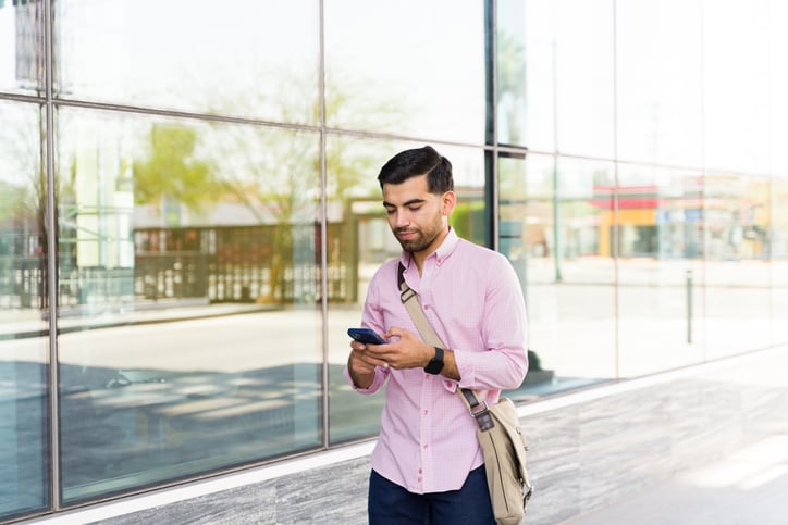 Un homme marche dans la rue en consultant son smartphone