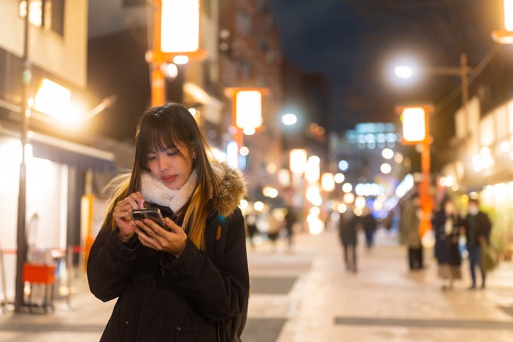 Une jeune femme marche dans la rue en consultant son smartphone