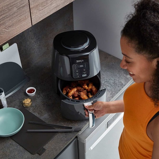 jeune femme utilisant un Airfryer pour cuire son poulet