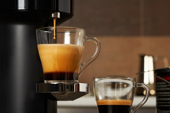 gros plan sur une tasse en verre avec du café provenant d'une machine